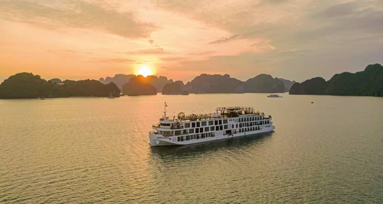 Kreuzfahrtschiff segelt in der Halong-Bucht bei Sonnenuntergang.