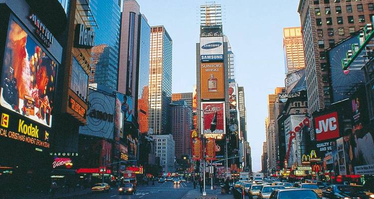 Times Square vibrant avec ses panneaux publicitaires imposants, ses taxis et ses gratte-ciel en plein jour.