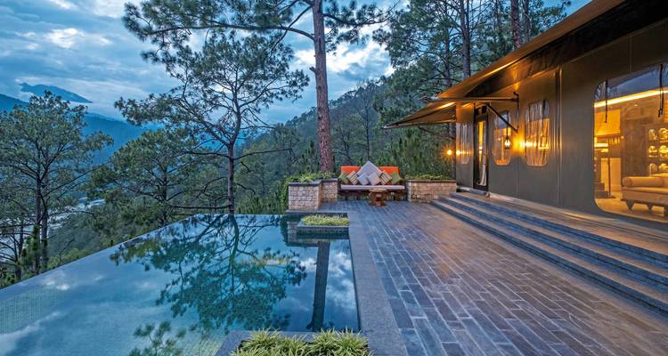 Luxusunterkunft mit Infinity-Pool mit Blick auf bewaldete Berge.