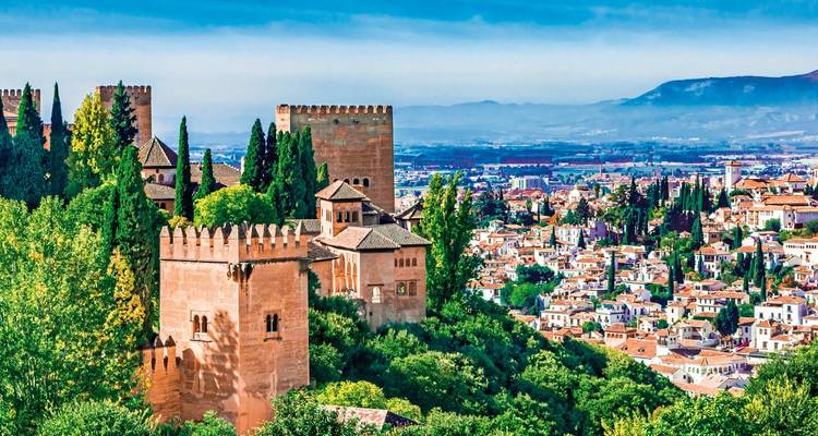 El palacio de la Alhambra con vista a la ciudad y montañas al fondo.