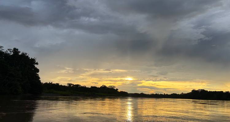 Coucher de soleil sur une rivière calme entourée d'arbres.