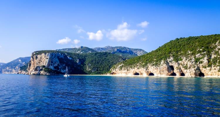 Rocky limestone cliffs and sea caves line a tranquil sapphire coastline.