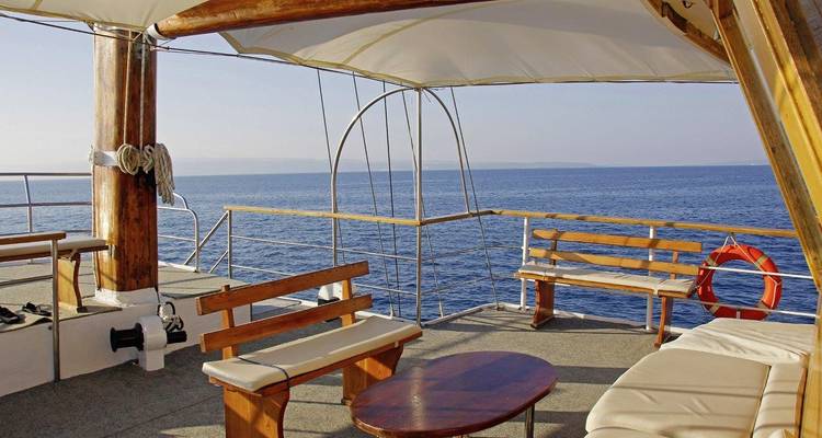 Deck area of a boat with wooden seating and an ocean view.