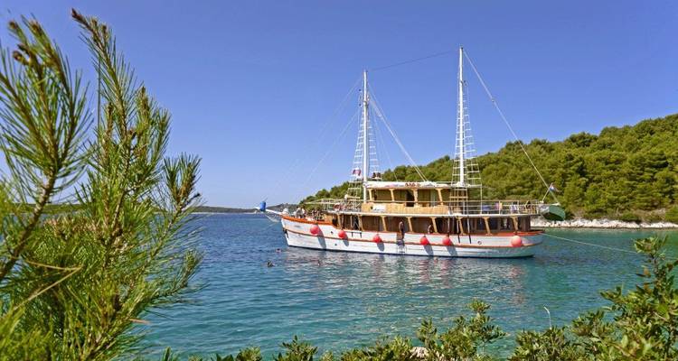 Boat cruising in a serene bay surrounded by hills.