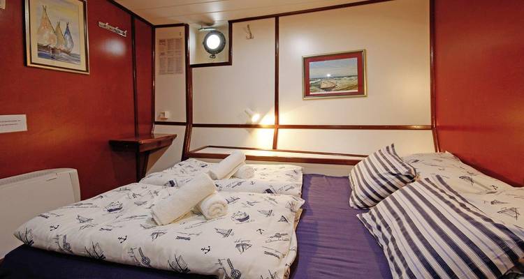 Cozy cabin room with a nautical theme and plush bedding.
