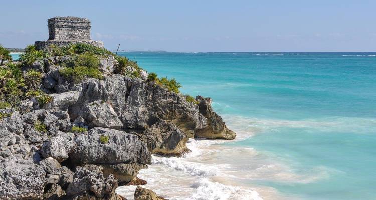 Una antigua ruina maya en el acantilado con vista al océano turquesa.