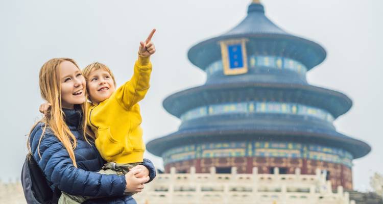 Vrouw die een kind vasthoudt en wijst naar een traditionele Chinese pagode.