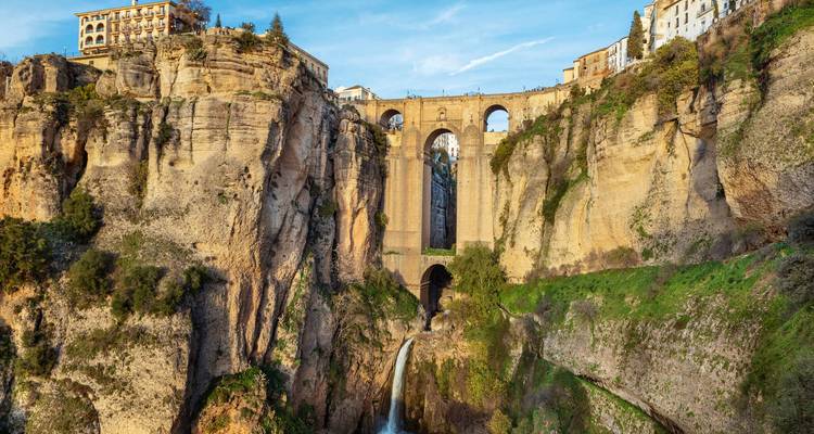 Eine große Steinbrücke, die eine tiefe Schlucht mit fließendem Wasser darunter überspannt.