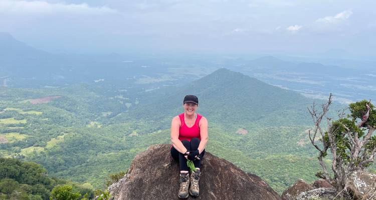 Woman sitting on a rock with expansive mountain views.
