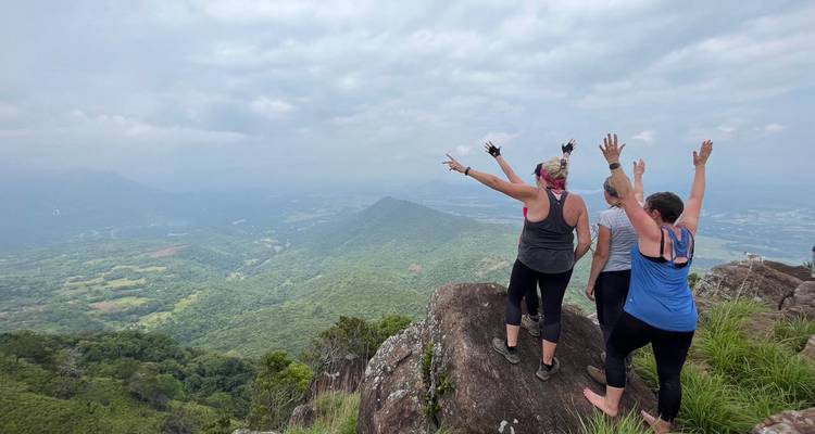 Three people on a peak with stunning views of a vast valley.