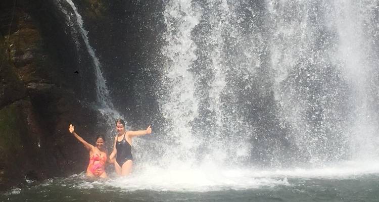 Two women posing in front of a flowing waterfall.