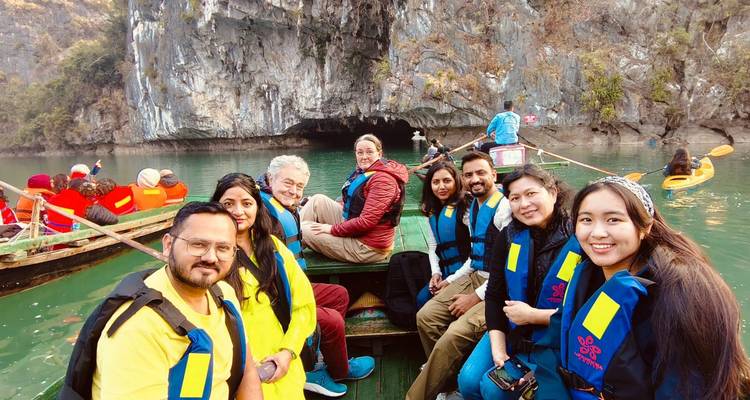 Groupe de touristes lors d'une excursion en bateau devant des formations de grottes dans une baie.