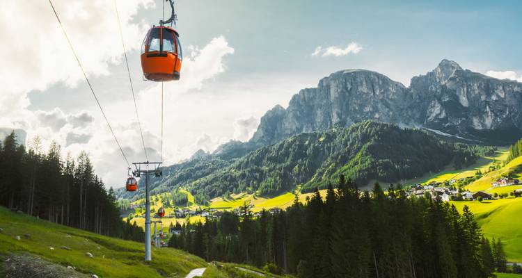 Les télécabines orange vif glissent le long d'un câble face aux pics spectaculaires des Dolomites et aux vallées luxuriantes.