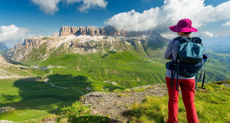 Un routard coiffé d'un chapeau de soleil rose contemple les vastes vallées verdoyantes qui s'étendent jusqu'aux falaises calcaires escarpées.
