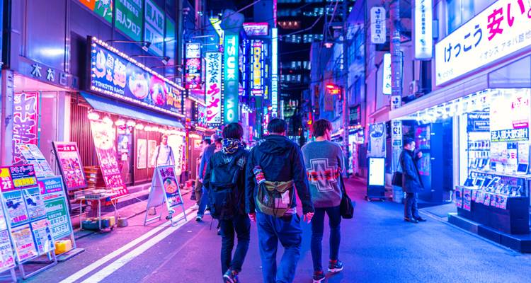 Rue éclairée au néon avec des gens qui passent devant les magasins.