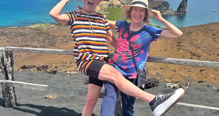 Deux voyageurs prenant une pose amusante à un point de vue côtier volcanique aux Galápagos.