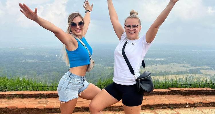 Two women posing energetically at a scenic viewpoint.