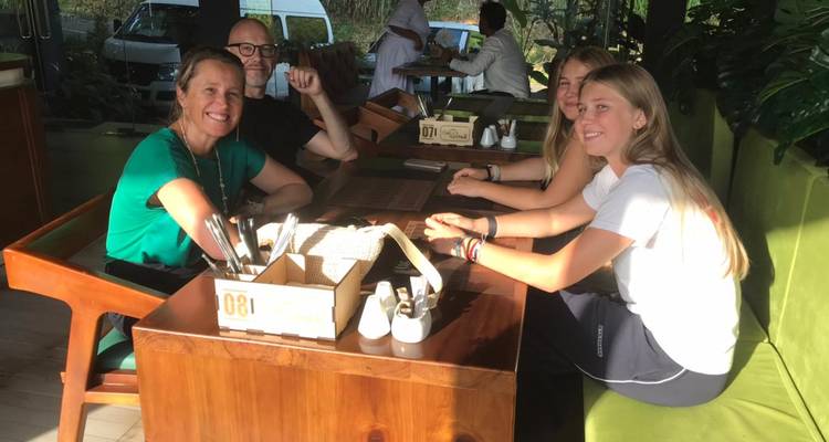 Four people sitting at a table in an outdoor dining area with sunlight.