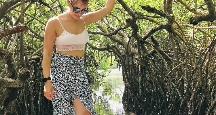 Woman walking among mangrove trees.