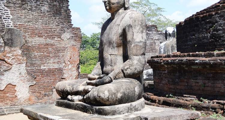Ancient stone statue of a seated Buddha in ruins.