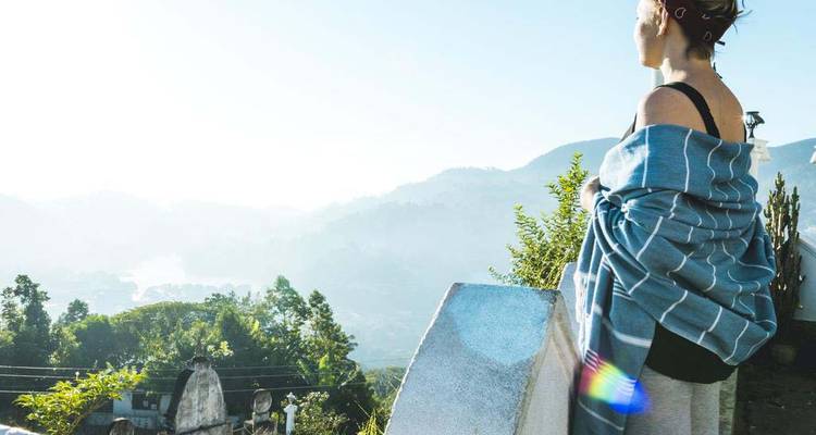 Person, die auf eine neblige Landschaft mit Grün blickt.