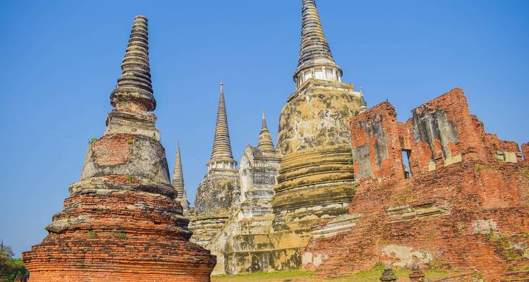 Stupas and ruins under a bright blue sky in Ayutthaya.