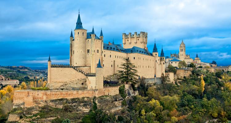 Un grand château historique sur une colline entouré de verdure.