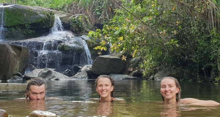 People enjoying swimming in a natural pool by a waterfall