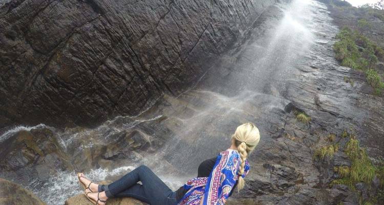 Woman sitting by a waterfall cliff