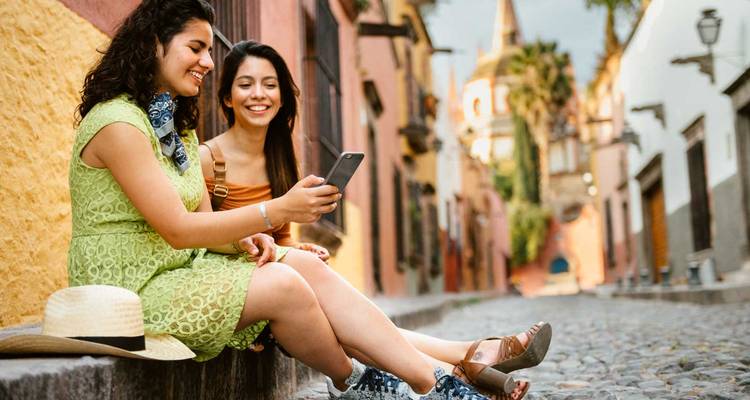 Two women sitting on a cobbled street