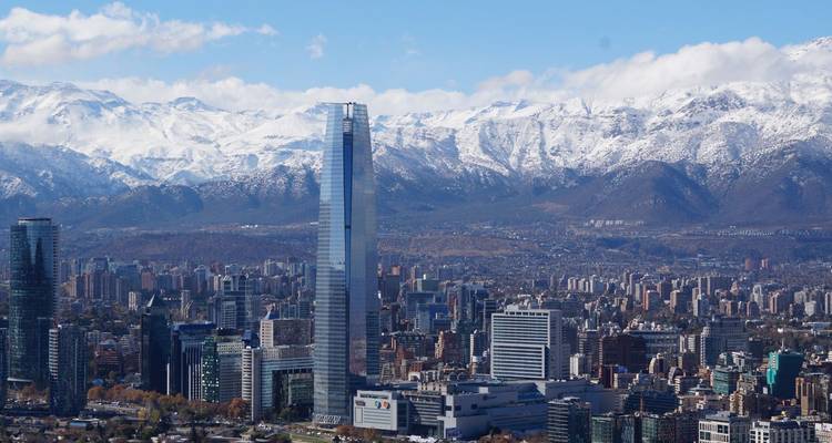 Horizon urbain avec des bâtiments modernes et des montagnes enneigées.
