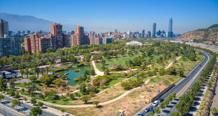 Parc urbain avec un étang et des sentiers de promenade entouré par un horizon urbain.