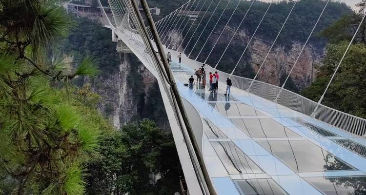 Des touristes marchant sur un pont de verre au-dessus d'un canyon.