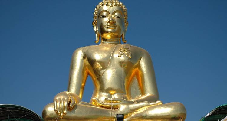 Large golden Buddha statue against a clear blue sky.