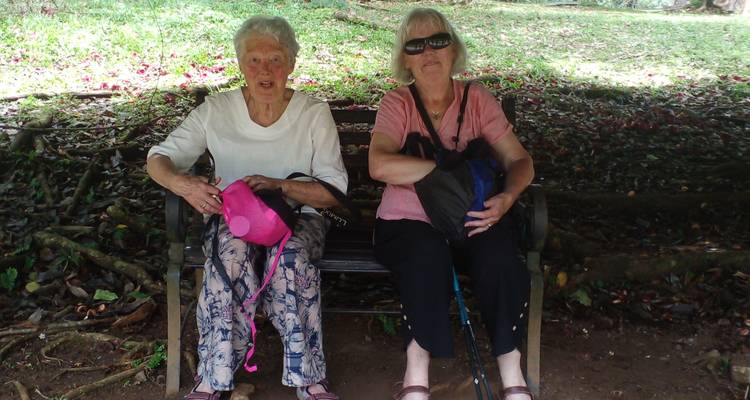 Deux femmes âgées assises sur un banc avec des sacs à dos.