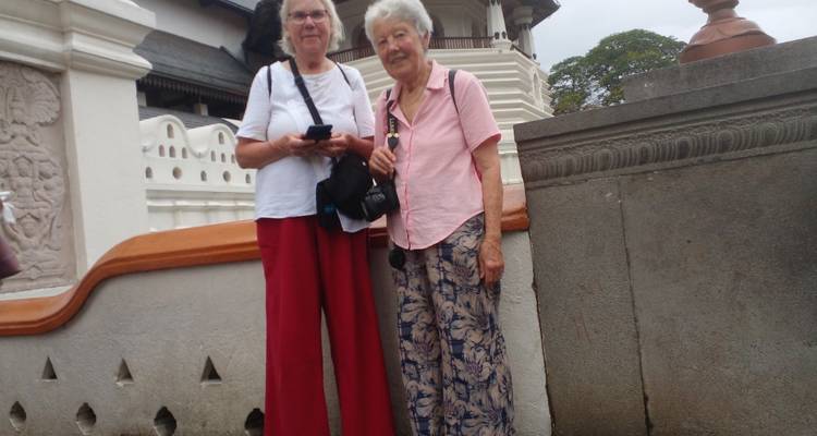 Deux femmes debout devant un bâtiment aux motifs complexes.