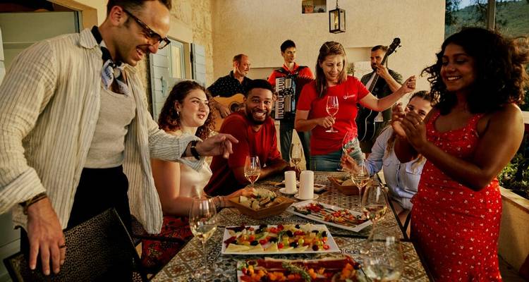 Des voyageurs savourant de la nourriture, du vin et de la musique d'accordéon en direct lors d'un dîner en terrasse.