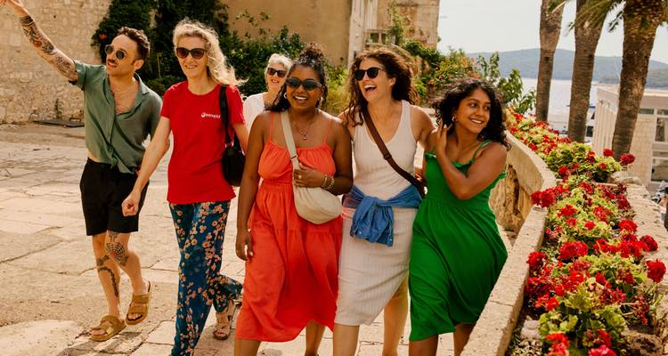 Groupe de femmes heureuses marchant le long d'une promenade fleurie par une journée ensoleillée.