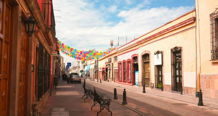Street view of colorful buildings decorated with flags.