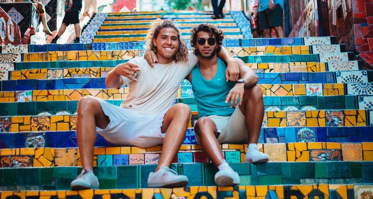 Deux amis souriants posent sur les marches colorées en mosaïque de l'Escadaria Selarón.