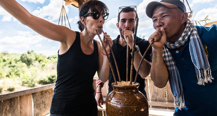 Group of people trying traditional drink using reeds.