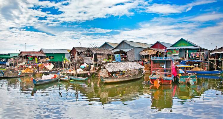 Floating village with colorful houses on stilts by a river.