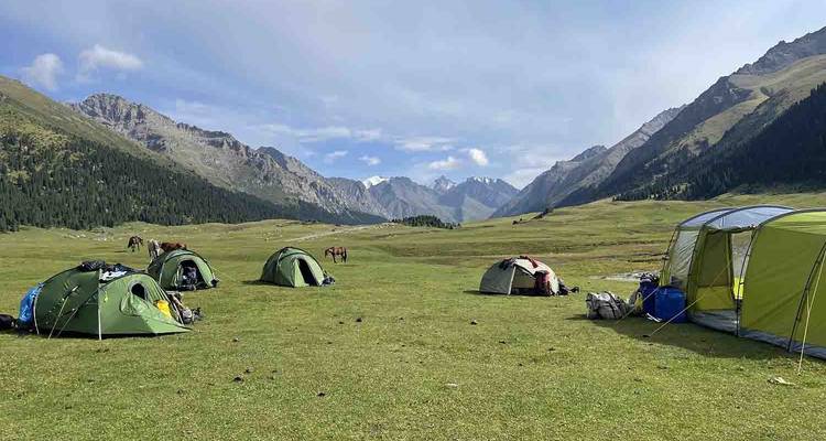 Un camping avec des tentes dans une vallée entourée de montagnes.