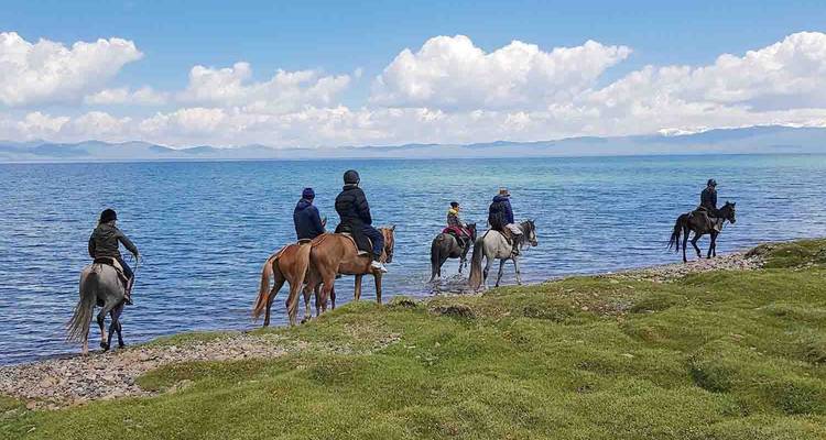 Groupe de personnes à cheval au bord d'un lac.