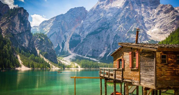 Mountain landscape with a wooden cabin by a lake.