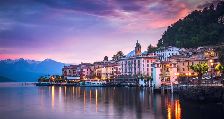 Zonsondergang boven een serene meer met bergen op de achtergrond.
