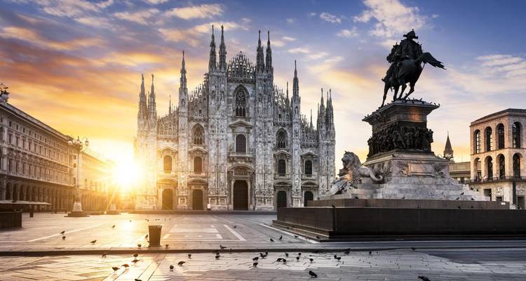 Duomo di Milano with a statue at sunrise.