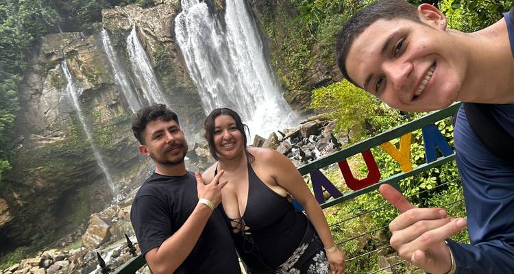 Trois personnes souriantes devant une cascade.