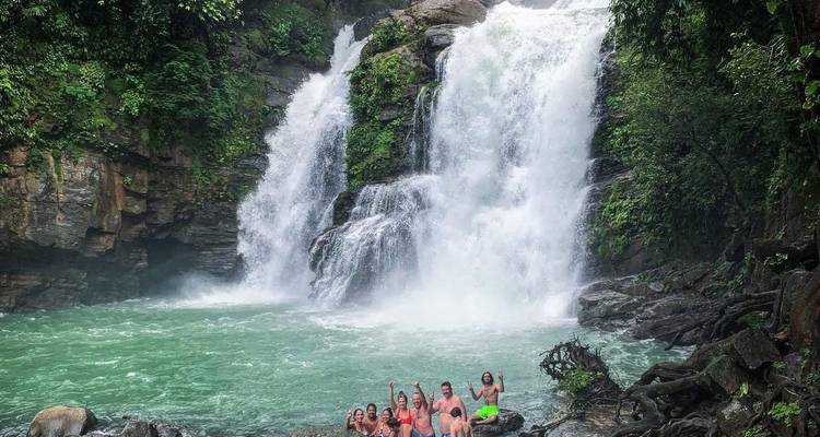 Groupe de personnes posant devant une grande cascade.
