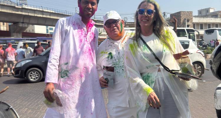 Trois personnes posant avec des poudres colorées pendant le festival de Holi.